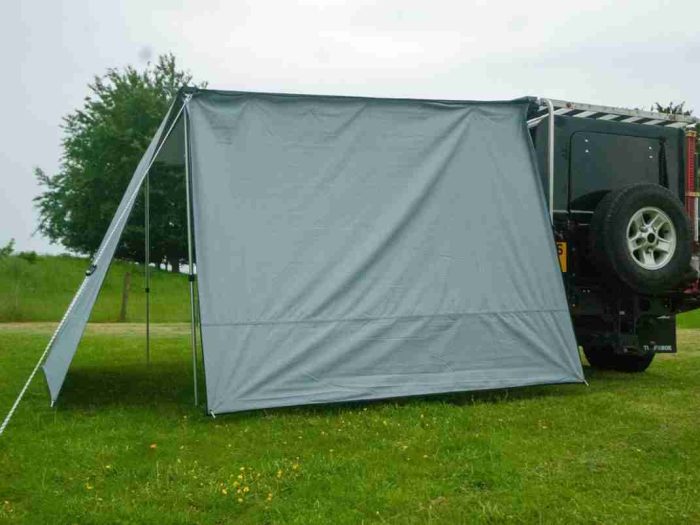 Vehicle side awning wall on a Land Rover in a UK grassy field.