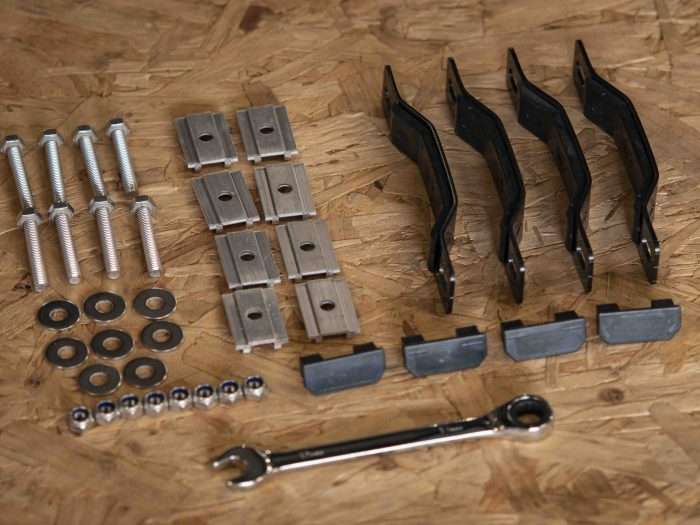 Roof tent fitting kit spread out on a wooden table including a spanner.